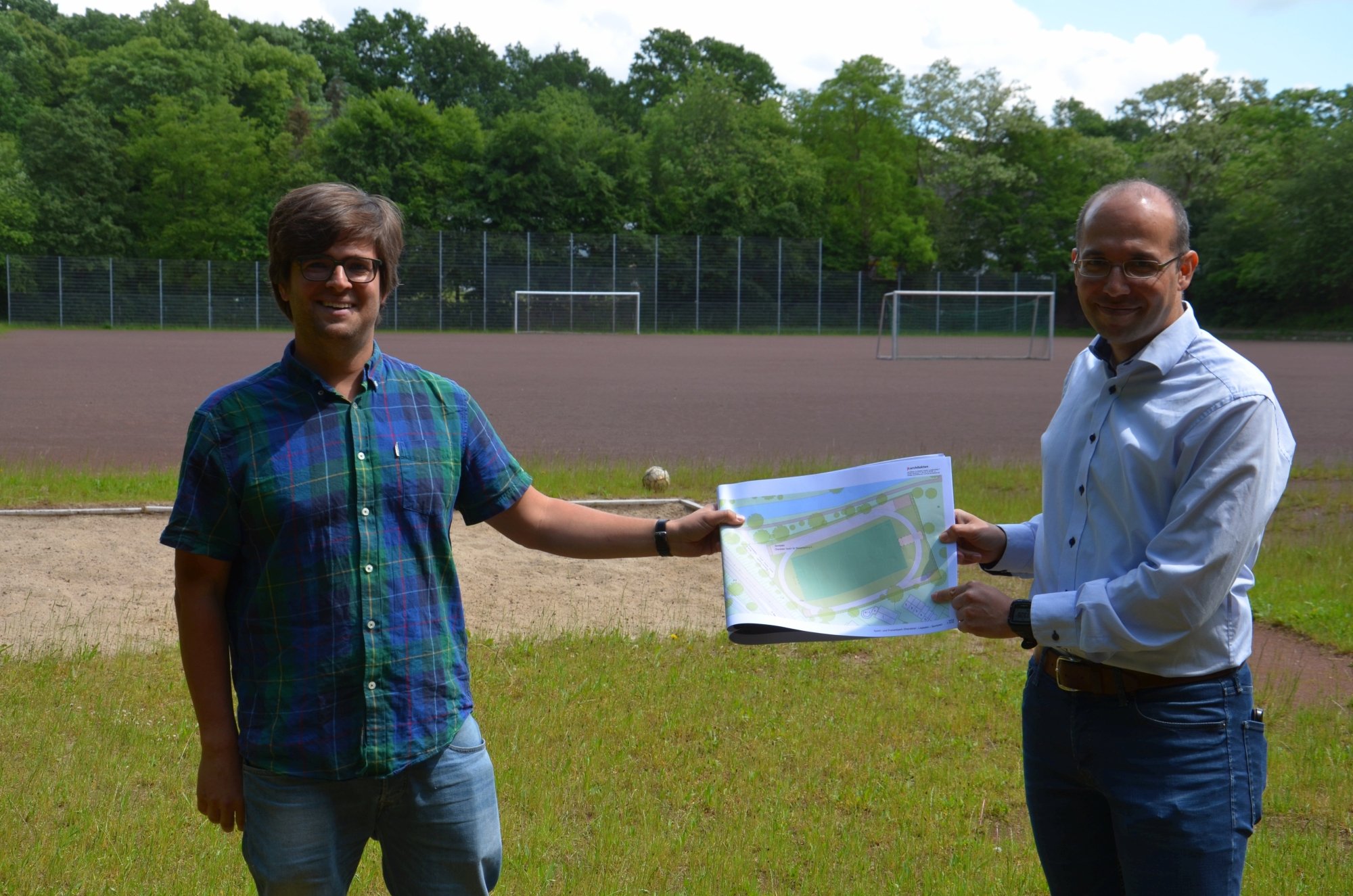 Timo B. Kranz (GRÜNE, links) und Nizar Müller (Oberalster VfW) mit einem ersten Entwurf für den neuen Sportplatz (Reiffert/GRÜNE Fraktion Hamburg-Nord)