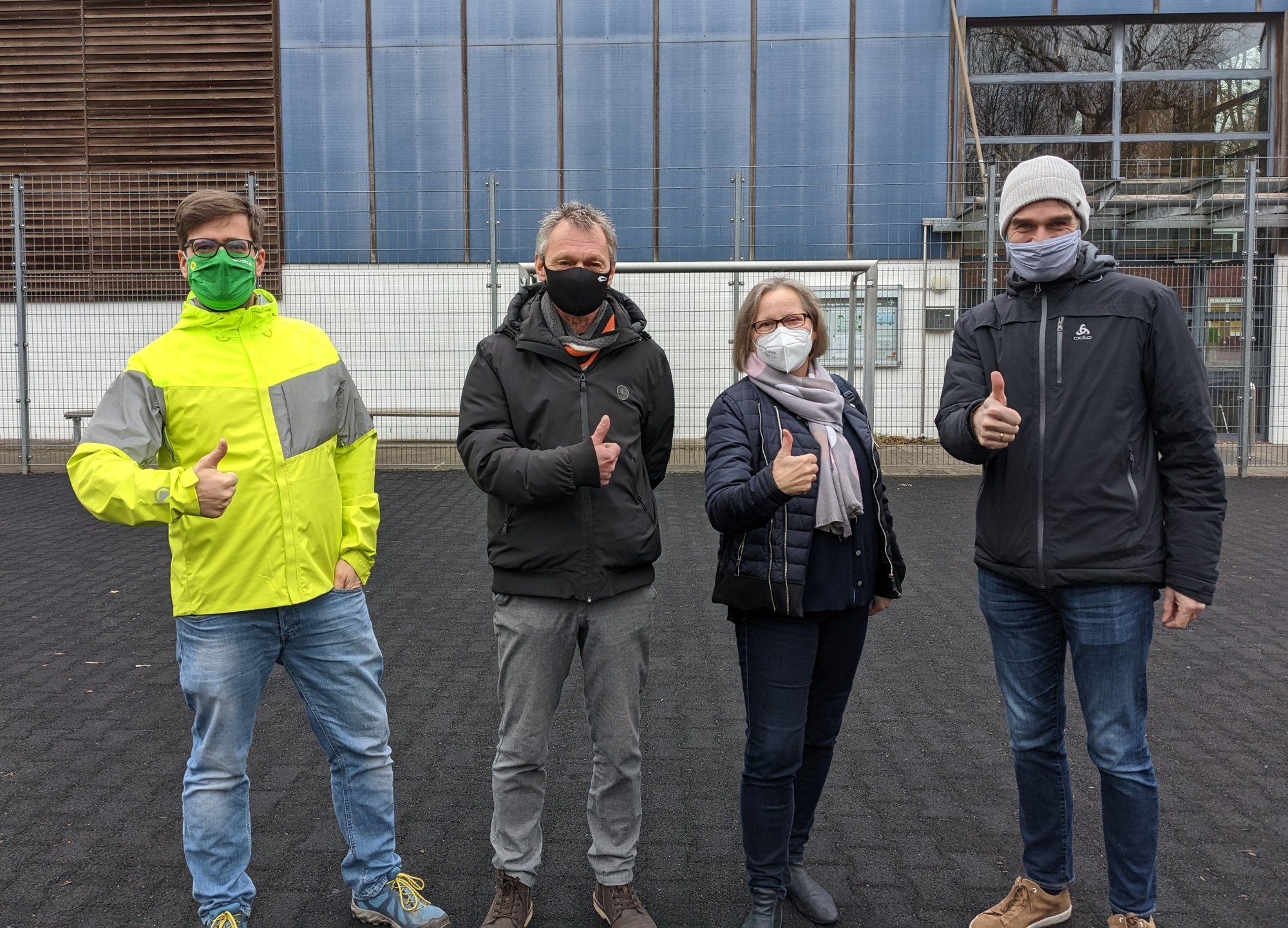 vlnr: Timo B. Kranz (GRÜNE), Michael Stuhr (Stellv. Vorsitzender SiB-Club), Maren Schindeler-Grove (1. Vorsitzende SiB-Club), Carsten Heinrich (Stellv. Schulleiter der Stadtteilschule Am Heidberg) auf der Fläche, die überdacht werden soll. Auf dem Schulgelände herrscht strenge Maskenpflicht