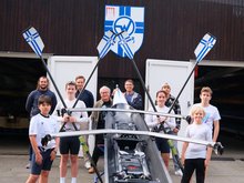 Oliver Camp (GRÜNE, rechts hinter dem Boot) und Nicklas Homuth (RVW, letzte Reihe, 2. von links) mit Trainern und Sportler*innen des Vereins